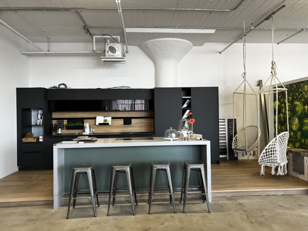Custom kitchen with dark cabinetry, open wood shelving and an island