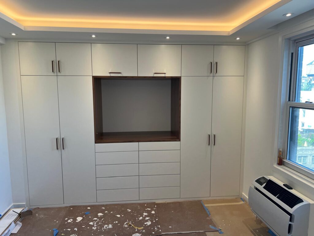 Built-in white wardrobe wall with a TV niche during installation