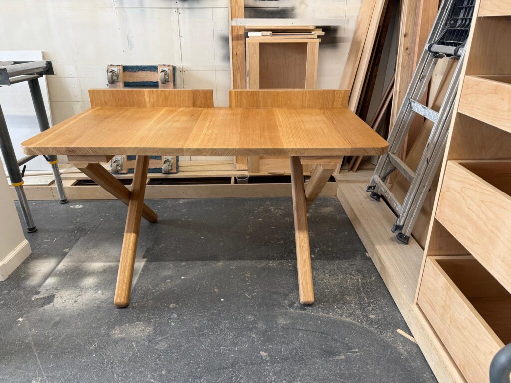 Solid wood table with crossed legs in the workshop